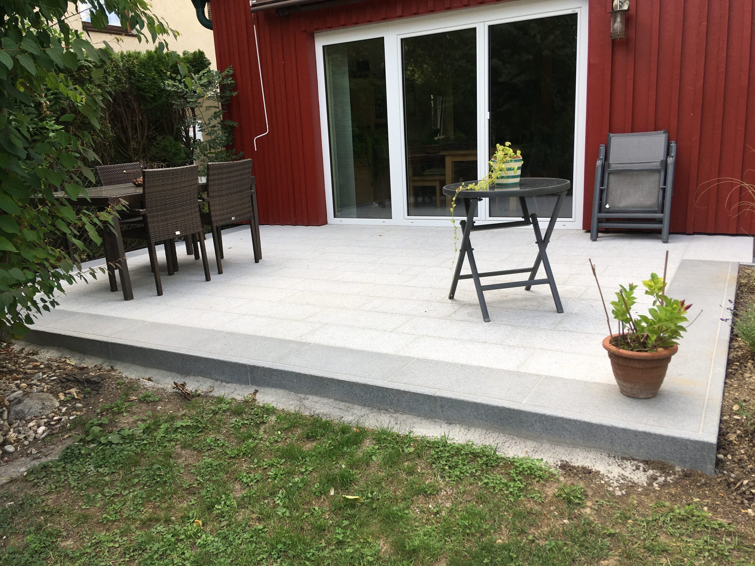 Terrasse mit hellen Steinplatten vor dem Haus