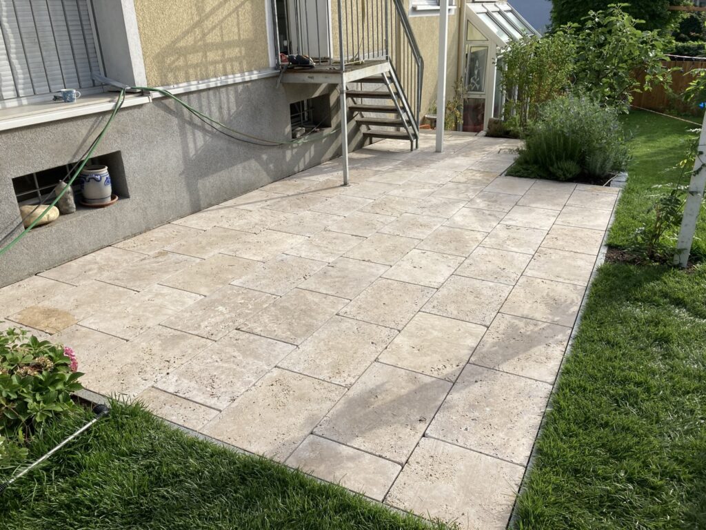 Terrasse mit hellen Steinplatten neben der Außentreppe
