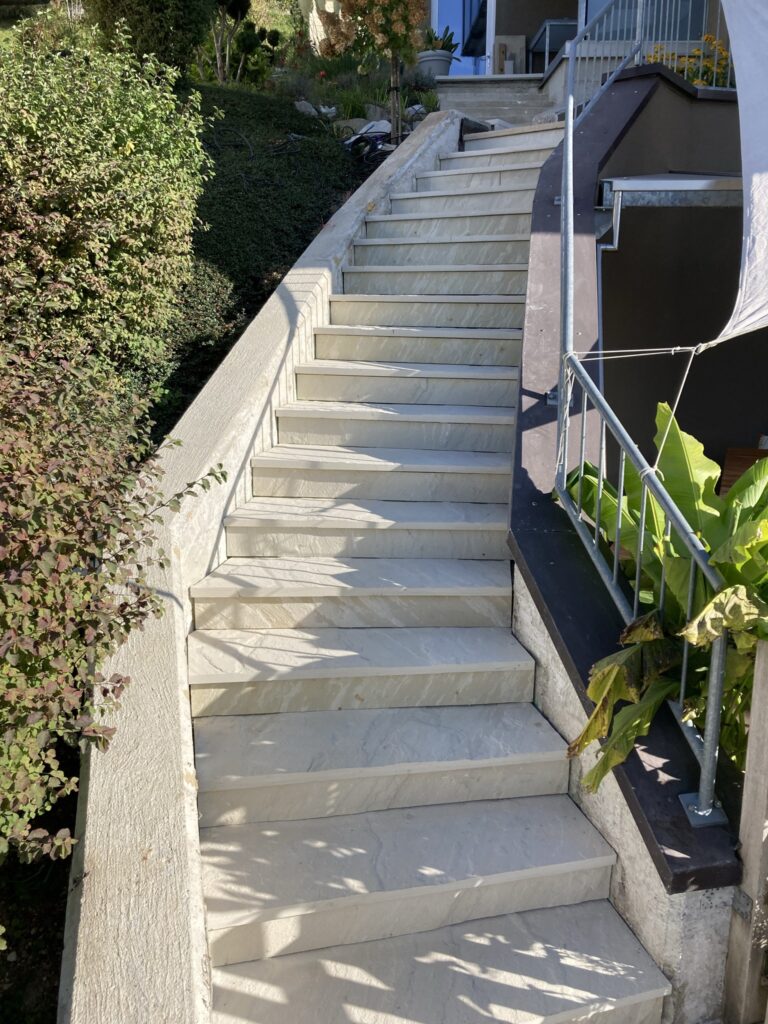 Außentreppe mit hellen Natursteinplatten und verkleideten Setzstufen