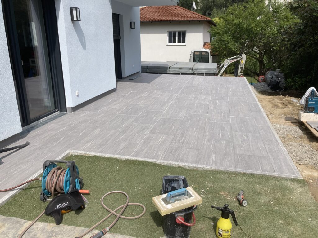 Großzügige Terrasse mit grauen Platten vor dem Wohnhaus