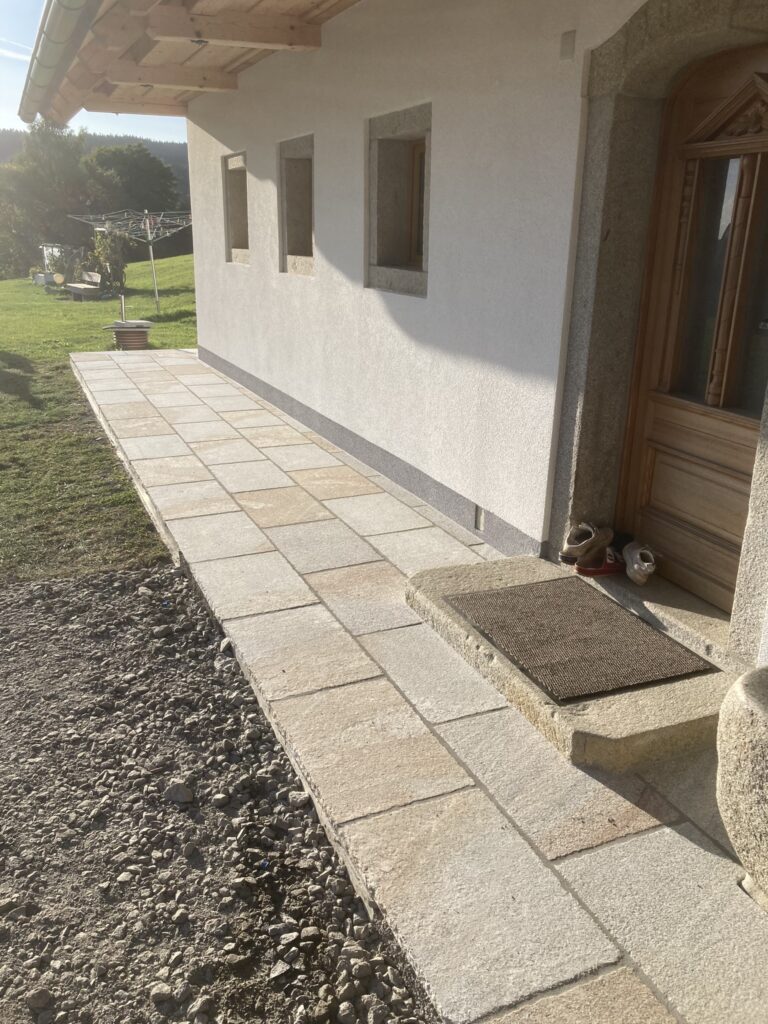 Hauszugang mit Natursteinplatten entlang der Fassade