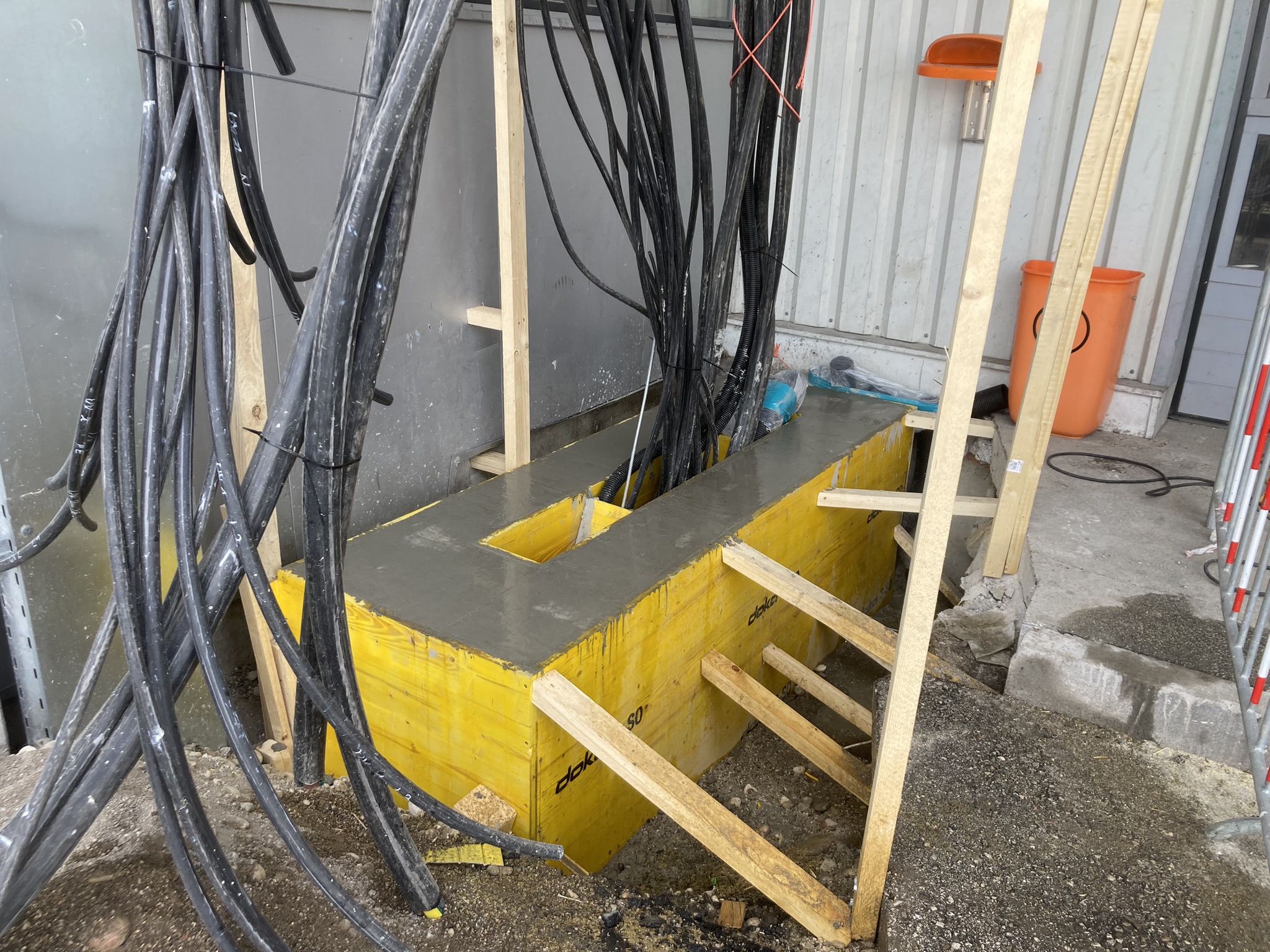 Frisch betoniertes Fundament mit Schalung und Kabeldurchführungen