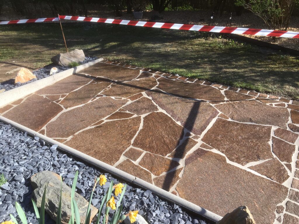 Gartenfläche mit braunen Polygonalplatten und hellen Fugen