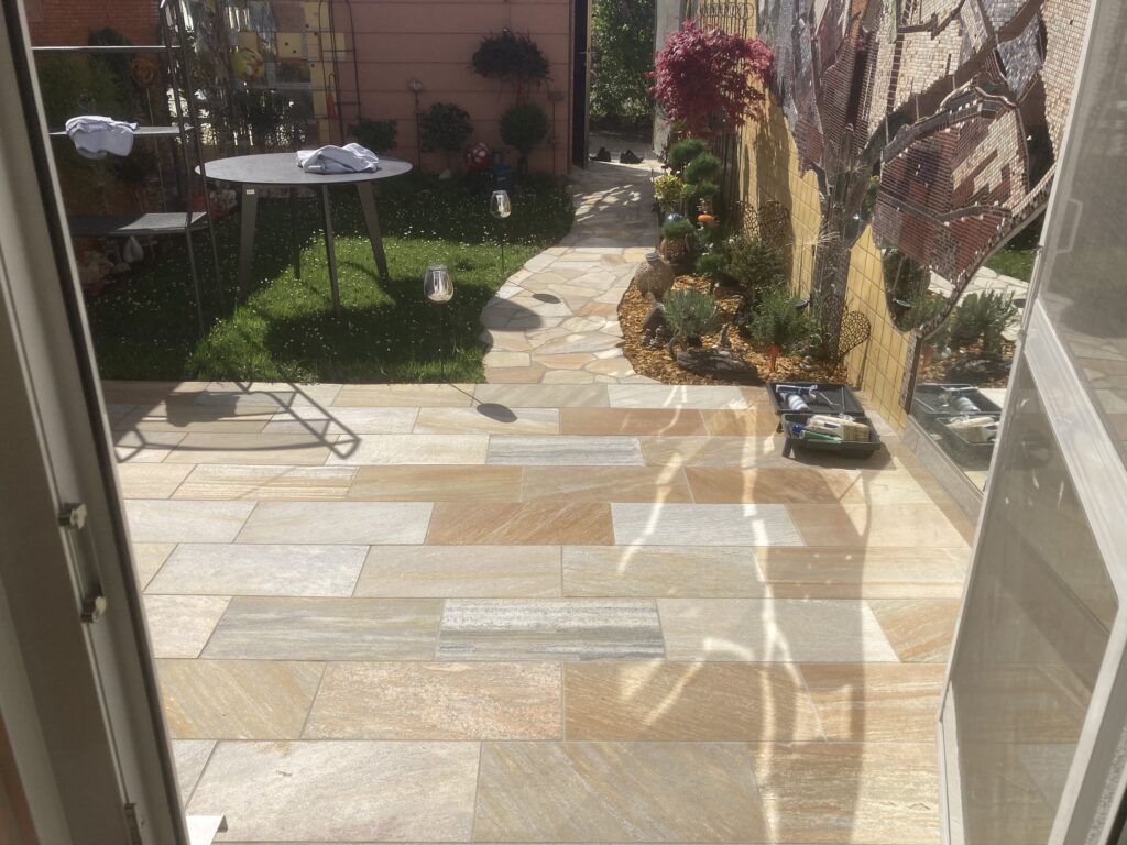 Terrasse mit Natursteinplatten und anschließendem Gartenweg aus Polygonalplatten